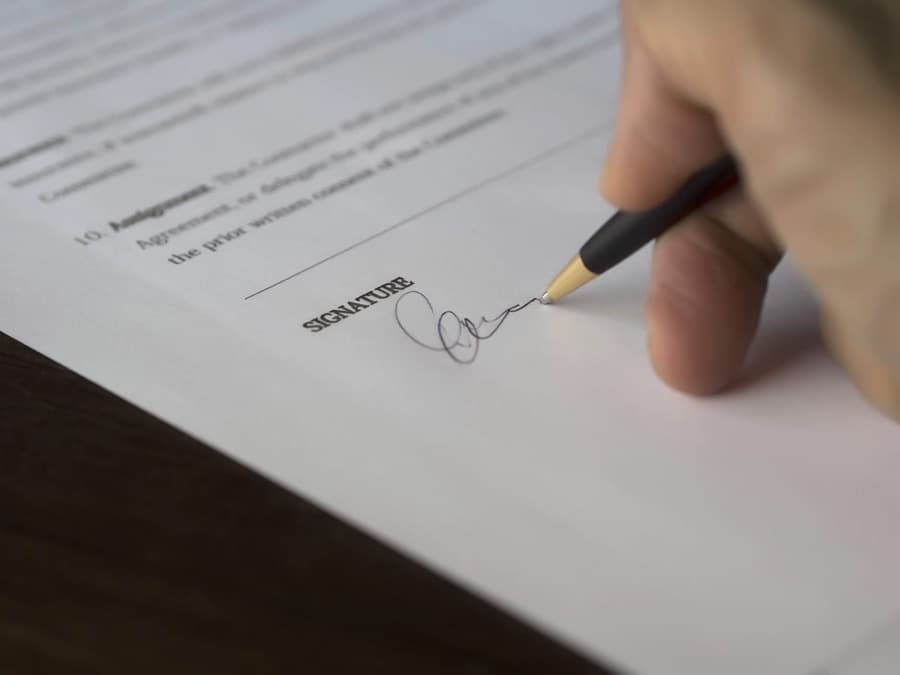 A hand signing a document